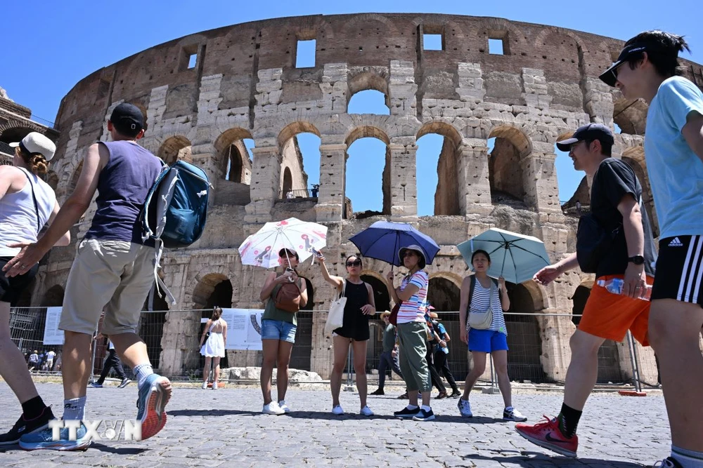 Khách du lịch che ô tránh nắng nóng khi tham quan Đấu trường La Mã ở Rome, Italy ngày 12/7/2024. (Ảnh: THX/TTXVN)