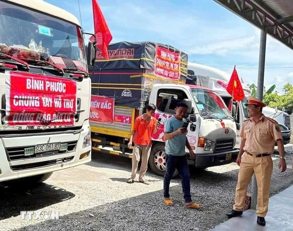 Cán bộ, chiến sĩ Cảnh sát giao thông Trạm Đức Phổ hỗ trợ người và phương tiện vận chuyển hàng cứu trợ dùng cơm miễn phí. (Ảnh: TTXVN)