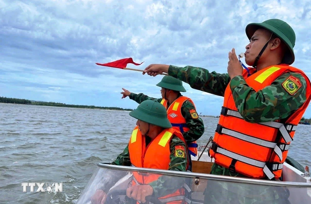 Cán bộ, chiến sỹ Đồn Biên phòng Lý Hòa (Bộ đội Biên phòng Quảng Bình) giúp ngư dân xã Đức Trạch, huyện Bố Trạch đưa thuyền lên bờ tránh trú. (Ảnh: TTXVN phát) 