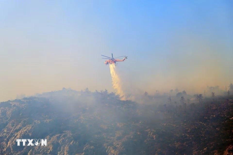 Trực thăng cứu hỏa tham gia dập đám cháy rừng gần ở Hy Lạp. (Ảnh: Reuters/TTXVN)