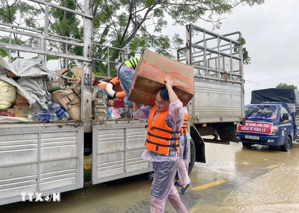 Các đoàn hỗ trợ vận chuyển lương thực và nhu yếu phẩm thiết yếu giúp người dân bị cô lập trong vùng lũ. (Ảnh: Tạ Toàn/TTXVN)