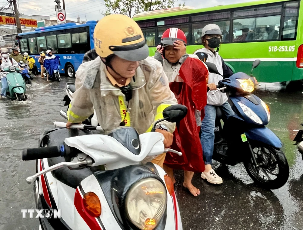 CSGT giúp người dân vượt qua vùng trũng, ngập úng sâu ở đoạn Quốc lộ 50 - Nguyễn Văn Linh, Quận 8. (Ảnh: Thanh Vũ/TTXVN)