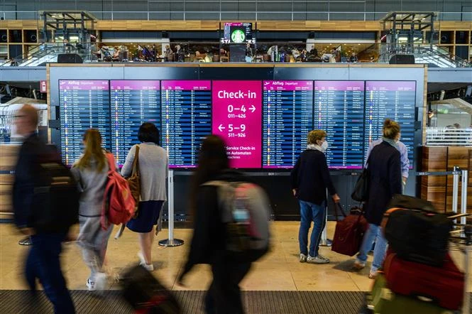 Hành khách kiểm tra thông tin các chuyến bay tại Sân bay Quốc tế Berlin Brandenburg (Đức). (Ảnh: AFP/TTXVN)