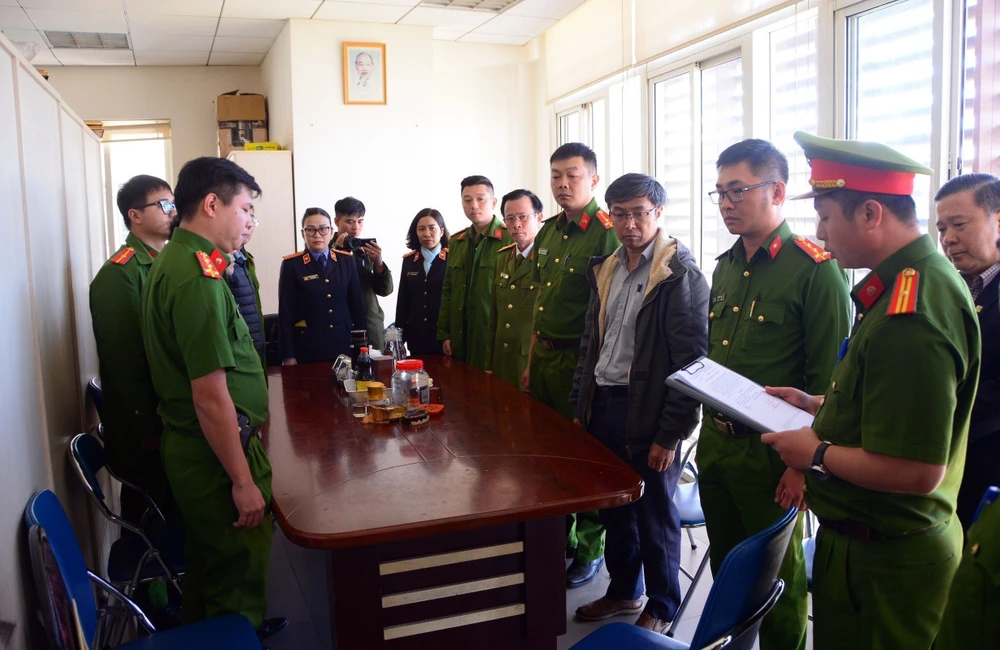 Cơ quan Điều tra đọc lệnh bắt Ngô Văn Thành (thường phục, phải) - Trưởng phòng Trung tâm Khuyến công và Tư vấn Phát triển Công nghiệp. (Ảnh: TTXVN phát)