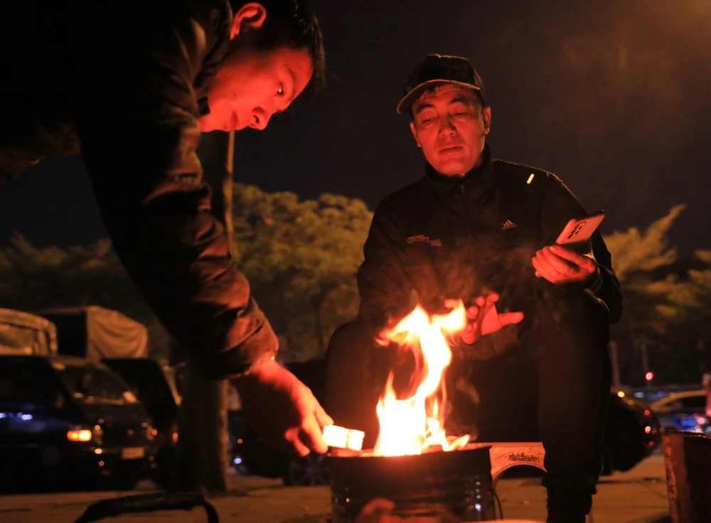 Người dân đốt lửa sưởi ấm gần cầu Long Biên (Hà Nội), tháng 12/2023. (Ảnh: Hoàng Hiếu/TTXVN)