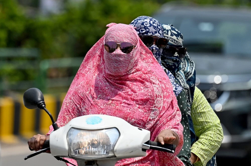 Người dân trùm kín tránh nắng nóng khi di chuyển tại Raipur (Ấn Độ) ngày 15/4/2024. (Ảnh: AFP/TTXVN)