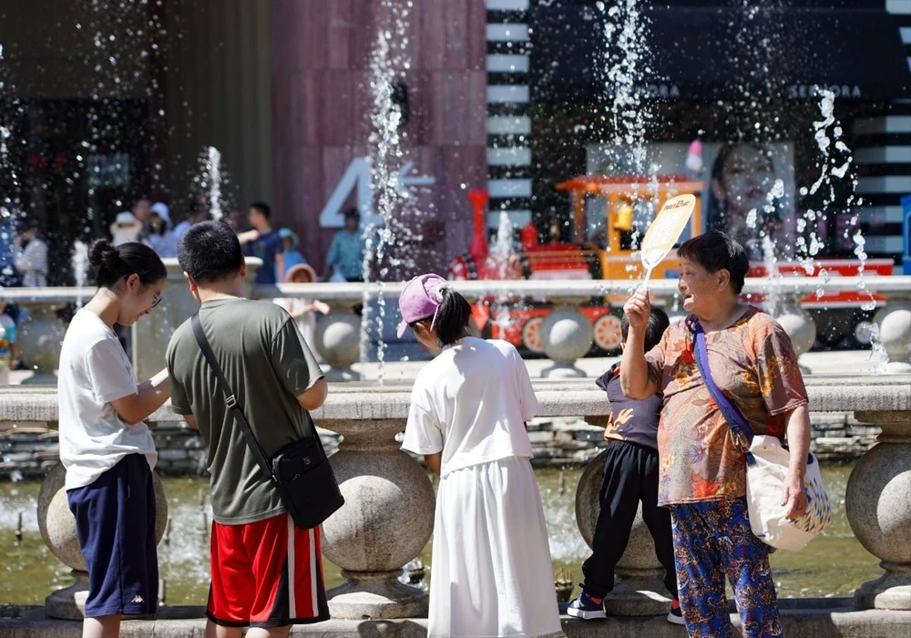 Người dân làm mát tại một đài phun nước trong ngày nắng nóng ở Bắc Kinh (Trung Quốc), ngày 9/6/2024. (Ảnh: THX/TTXVN)