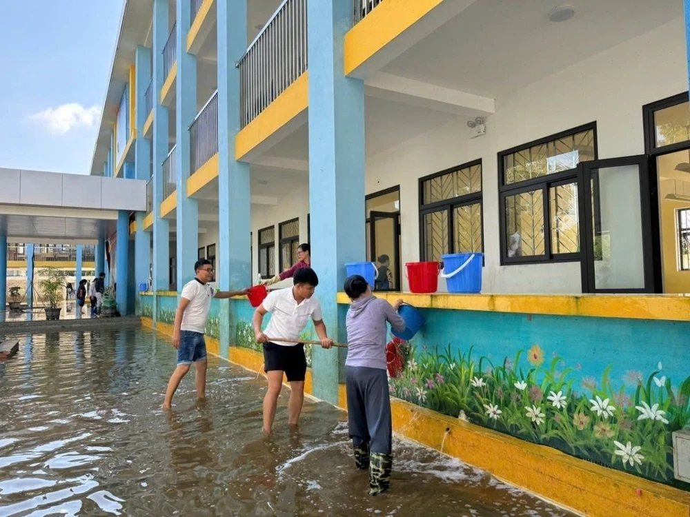 Giáo viên, nhân viên Trường Trung học Cơ sở Nam Phương Tiến A dọn vệ sinh trường lớp sau nhiều ngày bị ngập sâu, hôm 28/9 vừa qua. (Ảnh: Nguyễn Cúc/TTXVN)