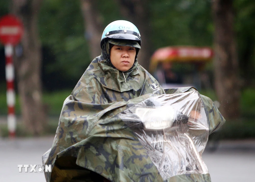 Người tham gia giao thông chống chọi với mưa rét trên đường Đinh Tiên Hoàng (Hà Nội). (Ảnh: Danh Lam/TTXVN)