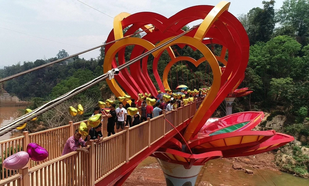 Du khách tham quan và trải nghiệm cầu kính tình yêu tại Khu du lịch sinh thái thác Dải Yếm, huyện Mộc Châu, tỉnh Sơn La. (Nguồn: TTXVN phát)
