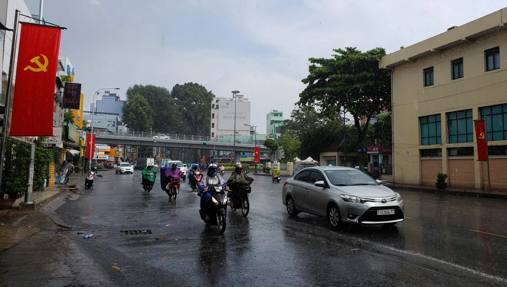 Người dân lưu thông trong mưa trên đường Thành Thái, Quận 10. (Ảnh: Xuân Dự/TTXVN)