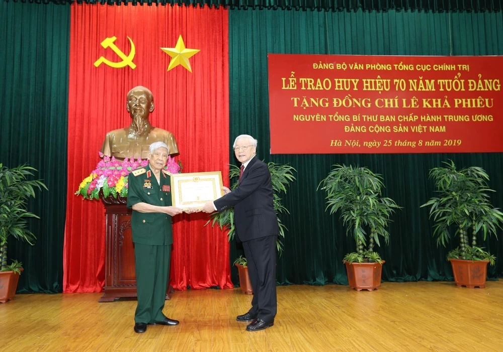 Tổng Bí thư, Chủ tịch nước Nguyễn Phú Trọng, Bí thư Quân ủy Trung ương trao Huy hiệu 70 năm tuổi Đảng tặng nguyên Tổng Bí thư Lê Khả Phiêu. (Ảnh: Trí Dũng/TTXVN)
