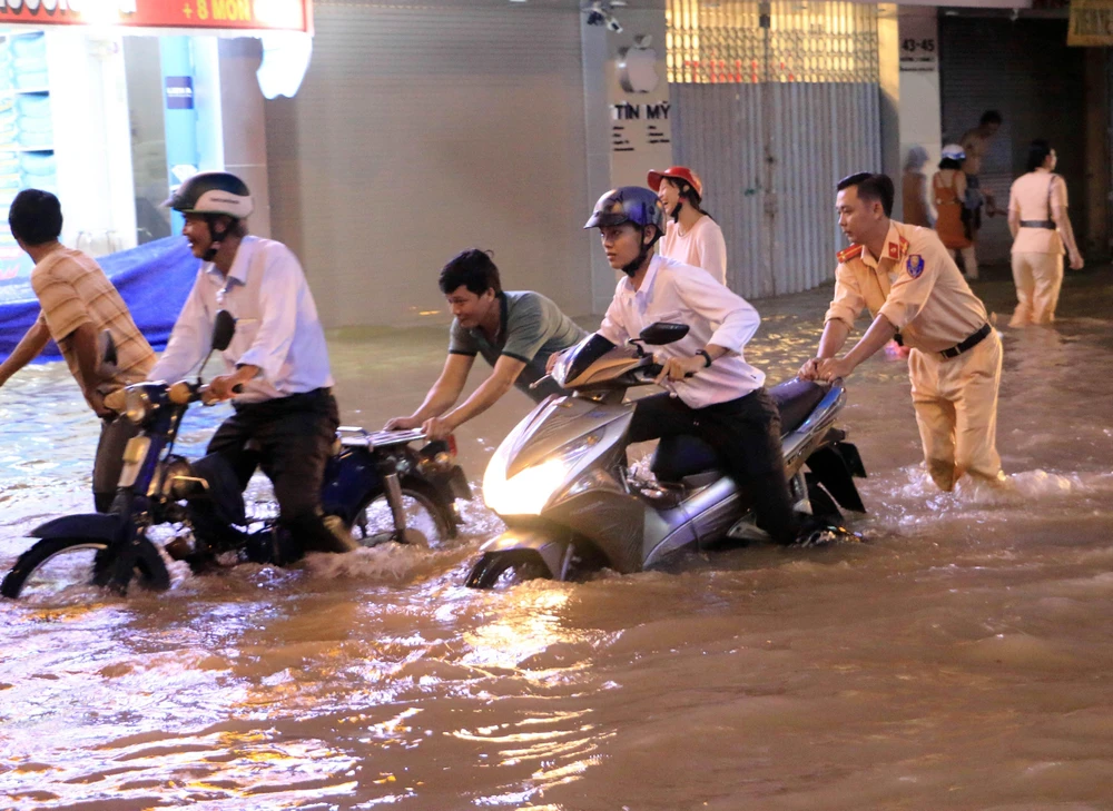 Lực lượng Công an giúp người điều khiển phương tiện giao thông di chuyển khỏi chỗ ngập tại đường 3 tháng 2, phường 1, thành phố Vĩnh Long. (Ảnh: Phạm Minh Tuấn/TTXVN)