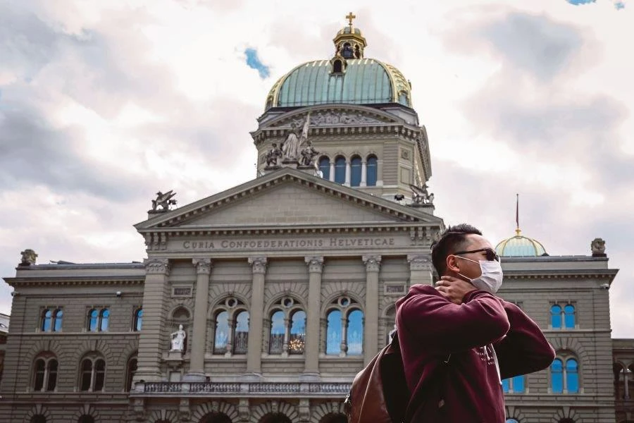 Một khách du lịch đeo khẩu trang được nhìn thấy trước Tòa nhà Quốc hội Thụy Sĩ vào ngày 13/3/2020, tại Bern. (Nguồn: AFP)