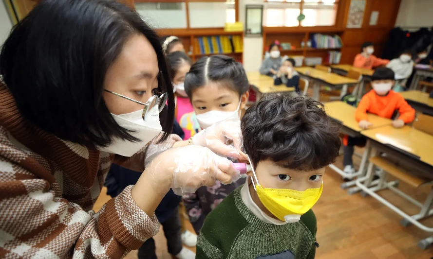 Một giáo viên kiểm tra thân nhiệt của học sinh trong bối cảnh lo ngại về dịch COVID-19 vùng phát khi các trường học trở lại sau kỳ nghỉ Đông ở Hàn Quốc. (Nguồn: Yonhap