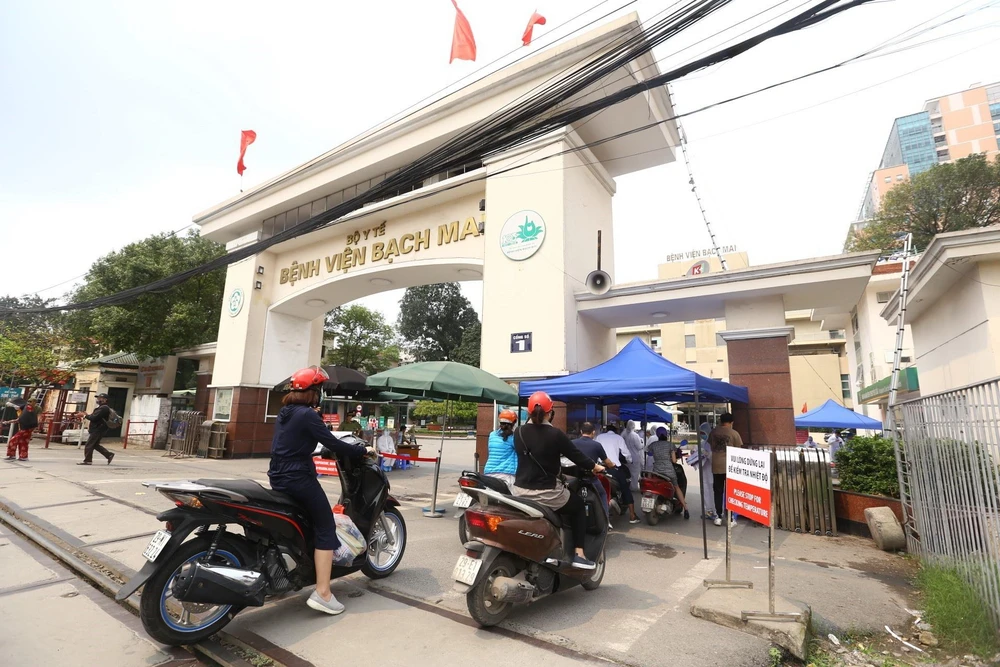 Tại cổng số 1 Bệnh viện Bạch Mai mọi hoạt động vẫn bình thường trong ngày 26/3, người dân khi vào cổng sẽ được đo kiểm tra thân nhiệt và sát khuẩn tay. (Ảnh: Minh Quyết/TTXVN)