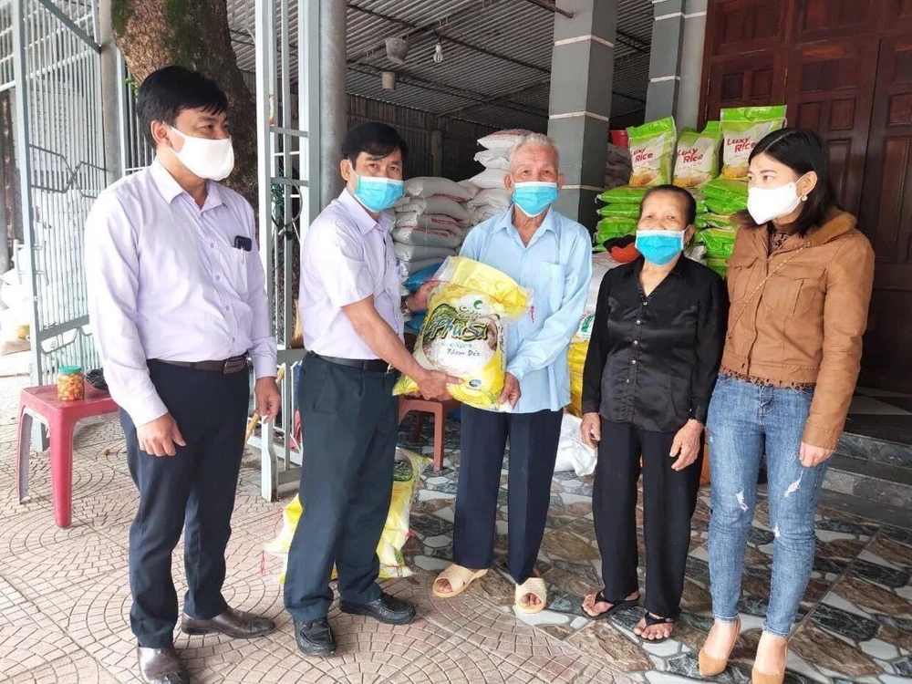 Vợ chồng cụ Nguyễn Hồng Phong trao số gạo cho đại diện chính quyền địa phương. (Ảnh: Hoàng Ngà/TTXVN)