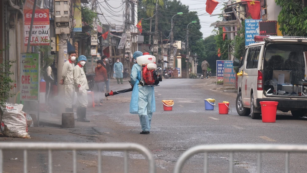 Lực lượng chức năng phun khử khuẩn tại thôn Hạ Lôi (Mê Linh). (Ảnh: Phạm Hùng/TTXVN phát)