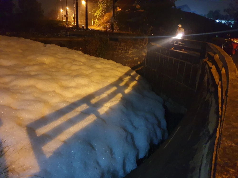 Bọt trắng nổi bất thường trên kênh thoát nước suối Chợ sau cơn mưa. (Nguồn: TTXVN phát)