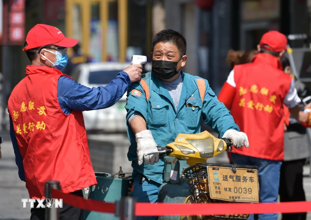 Tình nguyện viên kiểm tra thân nhiệt của người dân tại Vũ Hán, tỉnh Hồ Bắc, Trung Quốc ngày 15/4/2020. (Nguồn: THX/ TTXVN)