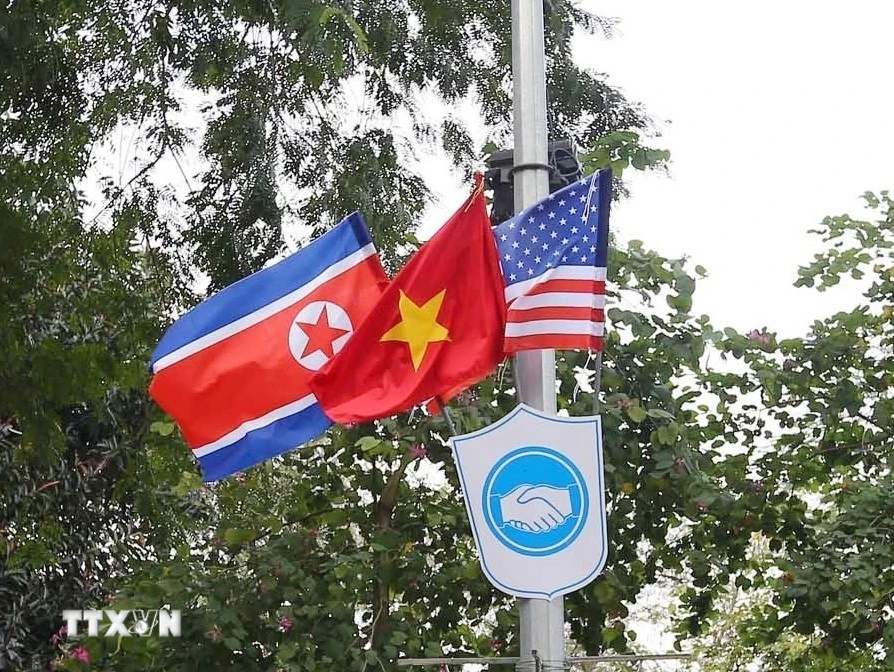 Cờ Mỹ, cờ Triều Tiên và cờ Việt Nam, bên dưới là biểu tượng hai bàn tay bắt chặt vào nhau thể hiện tinh thần của cuộc gặp lớn được treo trên các tuyến phố xung quanh hồ Hoàn Kiếm. (Ảnh: Danh Lam/TTXVN)