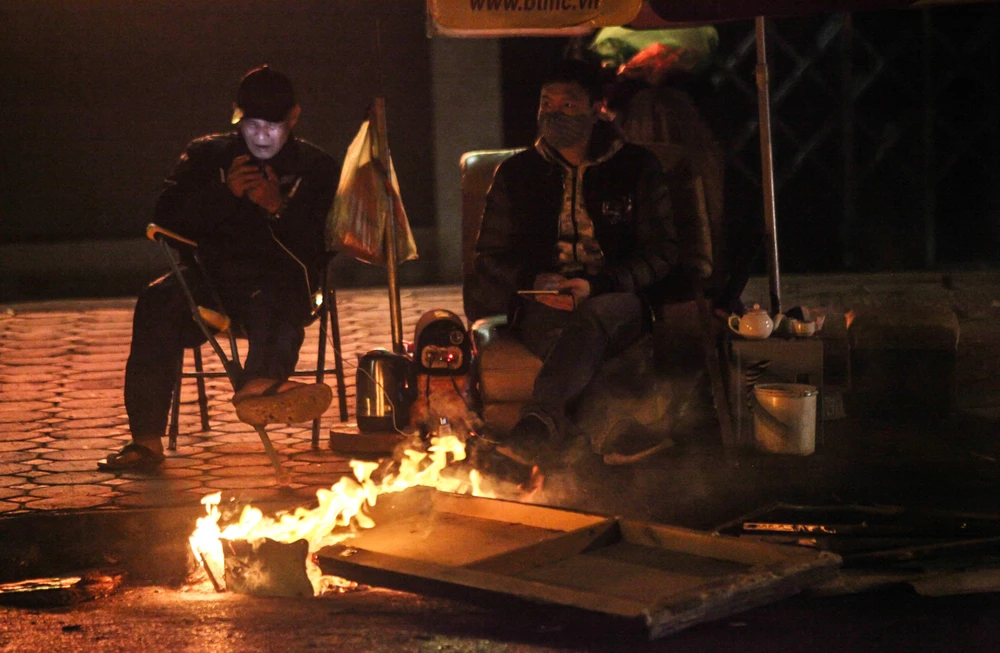 Người dân lao động đốt lửa, chống lại cái lạnh trong đêm 28/12/2018 trên phố Hào Nam. (Ảnh: Minh Hoàng/TTXVN phát)