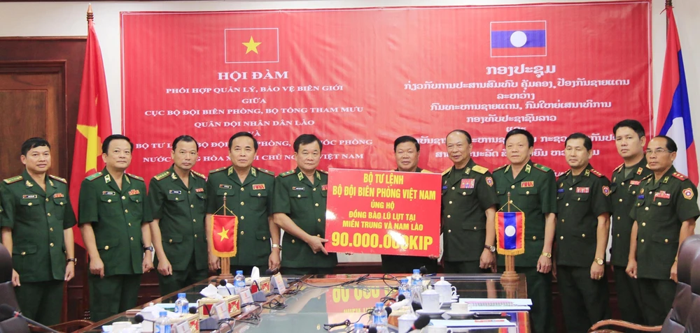 Trung tướng Hoàng Xuân Chiến (thứ 5, từ trái sang), Tư lệnh Bộ đội Biên phòng Việt Nam, trao tiền ủng hộ người dân bị thiệt hại tại các tỉnh Trung và Nam Lào cho Bộ Quốc phòng Lào. (Ảnh: Xuân Tú/TTXVN)