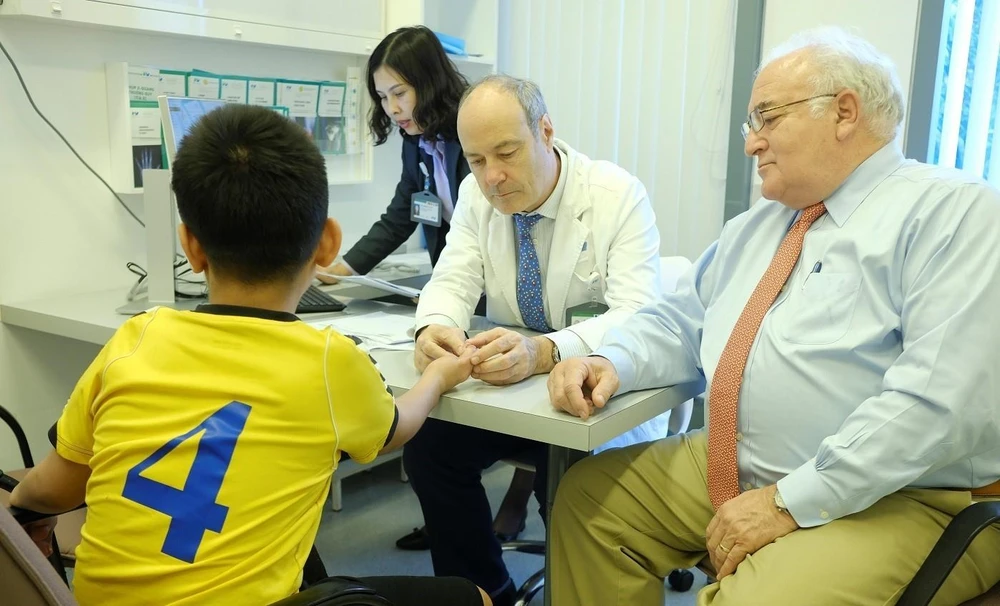 Bác sỹ Stéphane Guero (giữa) khám cho một bệnh nhi bị dị dạng ngón tay. (Ảnh: TTXVN phát)