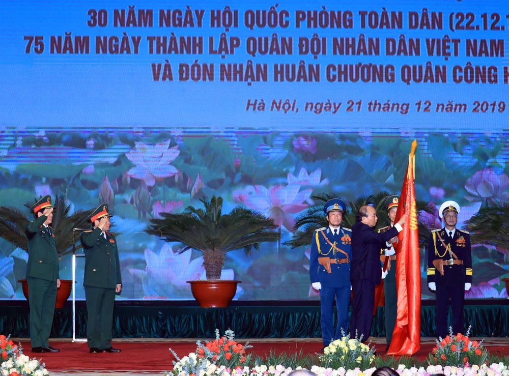 Thủ tướng Nguyễn Xuân Phúc, Chủ tịch Hội đồng thi đua - khen thưởng Trung ương trao tặng Huân chương Quân công hạng Nhất cho Bộ Quốc phòng. (Ảnh: Thống Nhất/TTXVN)