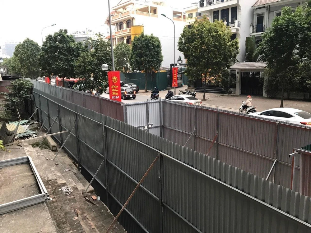 Hàng rào tôn đỏ do Công ty cổ phần May Lê Trực dựng, còn hàng rào màu ghi phía ngoài do UBND phường Điện Biên dựng. (Ảnh Minh Nghĩa/TTXVN)