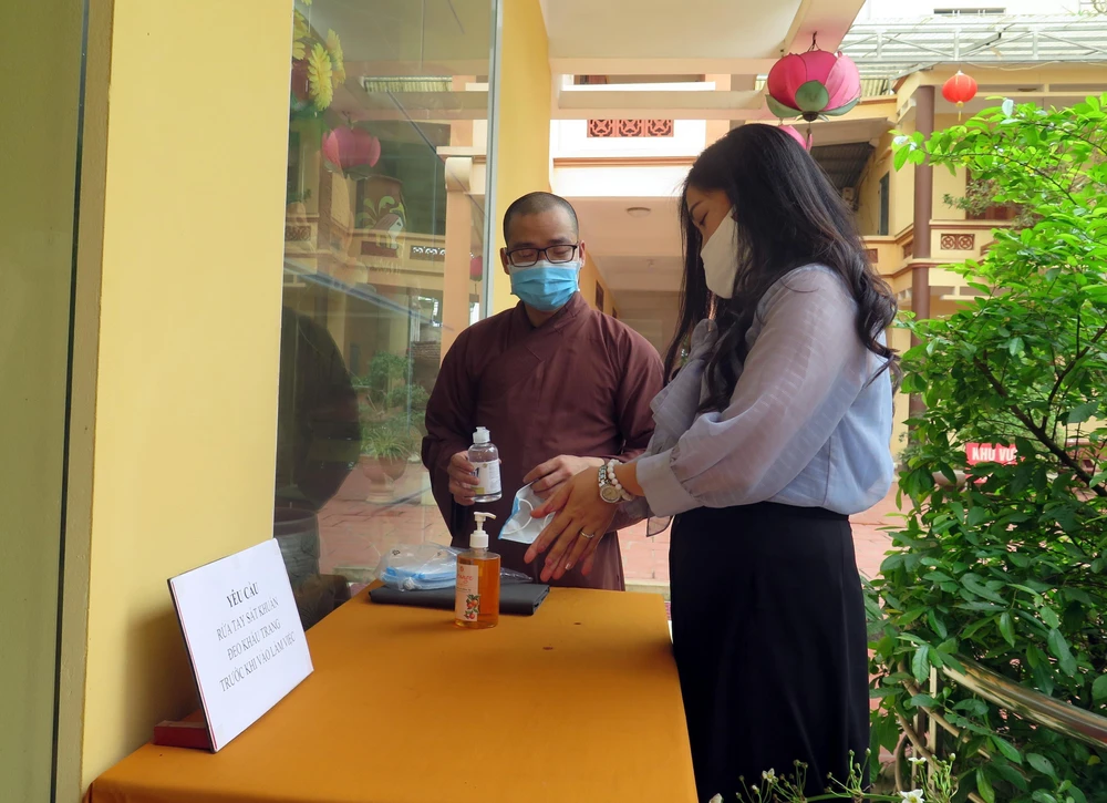 Sư thầy chùa Anh Vinh (thành phố Tuyên Quang) hướng dẫn người dân thực hiện rửa tay trước khi vào lễ chùa. (Ảnh Quang Đán/TTXVN)