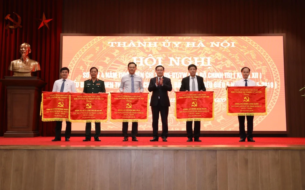 Bí thư Thành ủy Hà Nội Vương Đình Huệ trao tặng Cờ thi đua của Ban Thường vụ Thành ủy Hà Nội cho các Đảng bộ đạt thành tích xuất sắc trong nhiệm kỳ 2015/2019. (Ảnh: Văn Điệp/TTXVN)