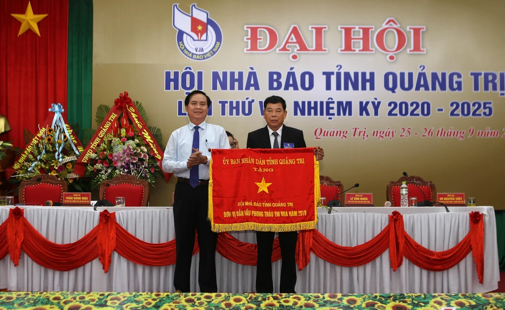 Chủ tịch UBND tỉnh Quảng Trị Võ Văn Hưng trao tặng Cờ thi đua đơn vị dẫn đầu phong trào thi đua năm 2019 cho Hội Nhà báo tỉnh. (Ảnh: Hồ Cầu-TTXVN)