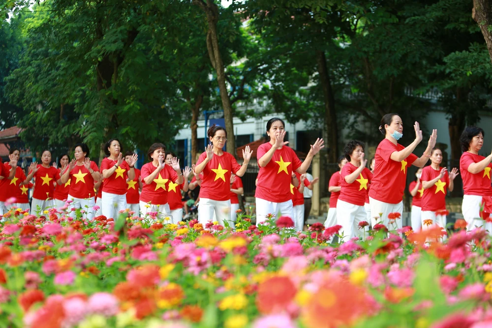 Người dân Thủ đô mặc đồng phục cờ Tổ quốc biểu diễn bài tập dưỡng sinh bên hồ Gươm sáng 2/9. (Ảnh: TTXVN)