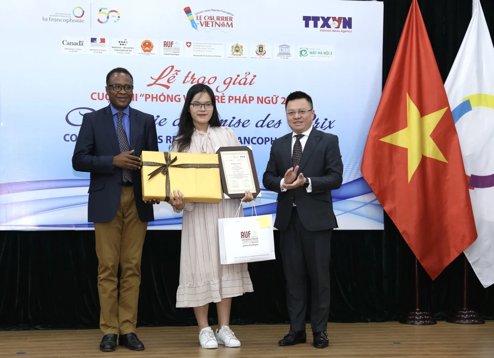 Phó Tổng giám đốc TTXVN Lê Quốc Minh và Trưởng đại diện khu vực châu Á-Thái Bình Dương của Tổ chức quốc tế Pháp ngữ OIF Chékou Oussouman trao giải Nhất cho tác giả Man Khánh Ly. (Ảnh: Hoàng Hiếu/TTXVN)