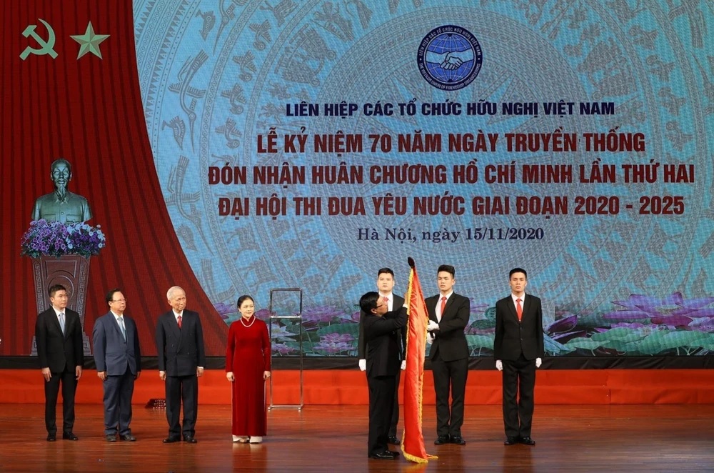 Phó Thủ tướng, Bộ trưởng Bộ Ngoại giao Phạm Bình Minh gắn Huân chương Hồ Chí Minh lên lá Cờ truyền thống của Liên hiệp các tổ chức hữu nghị Việt Nam. (Ảnh: Văn Điệp/TTXVN)