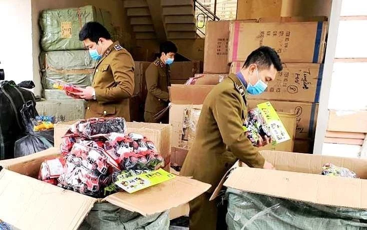 Lực lượng chức năng Cục Quản lý thị trường tỉnh Quảng Bình đang kiểm tra, xử lý vụ bắt giữ lô hàng giả, hàng nhập lậu. (Ảnh: TTXVN phát)