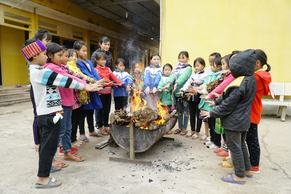 Cô và trò Trường Phổ thông Dân tộc Bán trú Tiểu học Leng Su Sìn (huyện Mường Nhé, Điện Biên) đốt lửa sưởi ấm. (Ảnh: Xuân Tư/TTXVN)