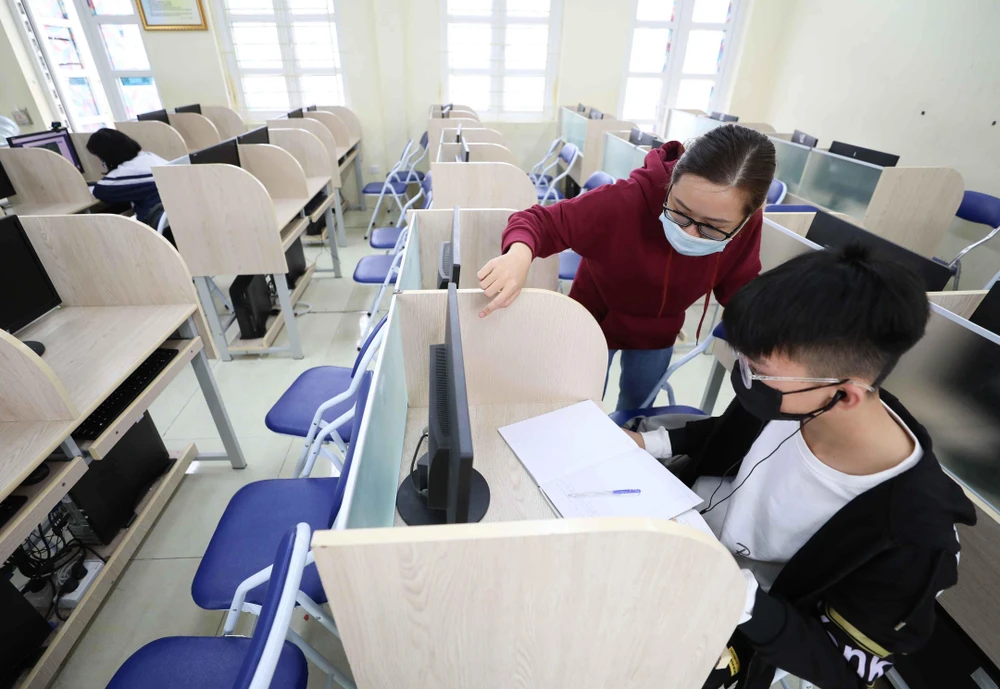 Học sinh trường THCS Thăng Long (Ba Đình, Hà Nội) không có điều kiện học trực tuyến tại nhà được nhà trường bố trí và phân công giáo viên giúp đỡ học tại phòng máy của trường. (Ảnh: Thanh Tùng/TTXVN)