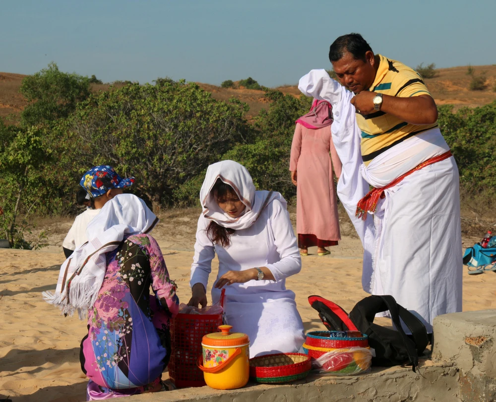 Chuẩn bị đồ cúng và mặc đồ truyền thống để thực hiện Lễ tảo mộ. (Ảnh: Nguyễn Thanh/TTXVN)