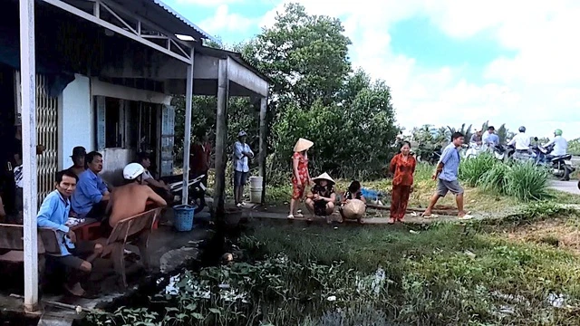 Người dân cùng chính quyền xã Tân Trung đến nhà Trần Minh Đắc giải cứu cháu bé 3 tuổi bị bạo hành. (Nguồn: Báo Thanh Niên)