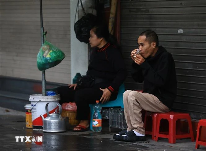 Thưởng thức cốc trà nóng trong mưa lạnh trên phố Trần Nhân Tông. (Ảnh: Hoàng Hiếu/TTXVN)