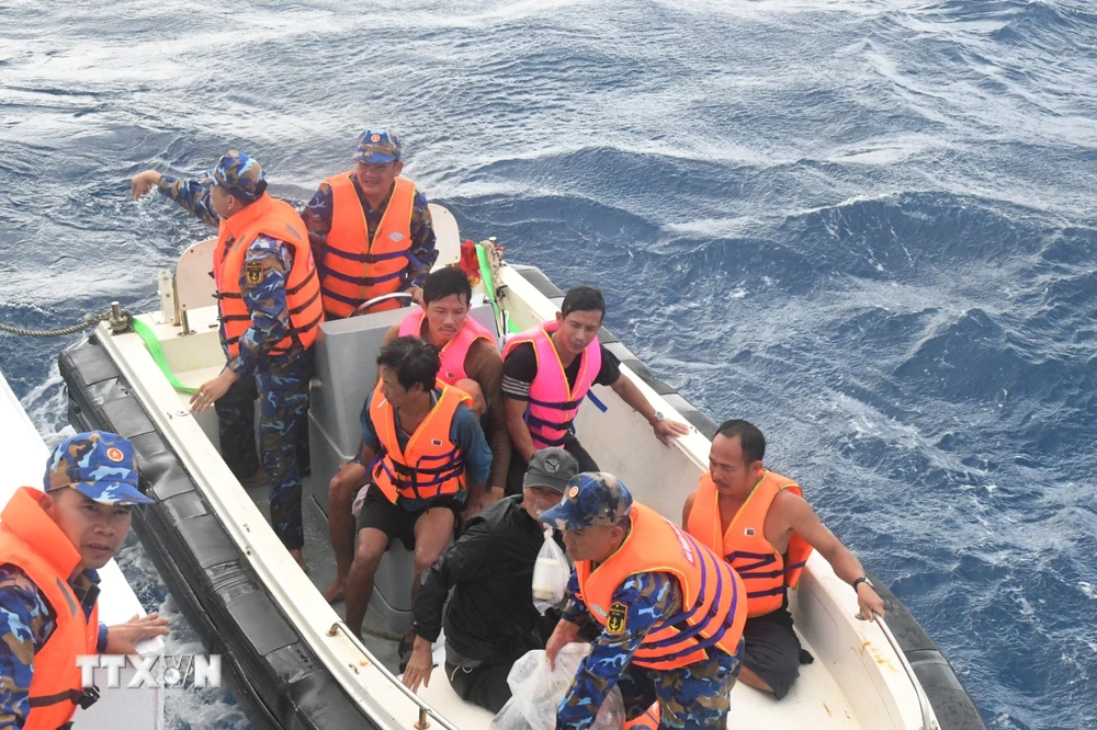 Lực lượng cứu nạn dùng xuồng nhỏ đưa 5 ngư dân (không mặc quân phục) về tàu 471. (Ảnh: TTXVN phát)
