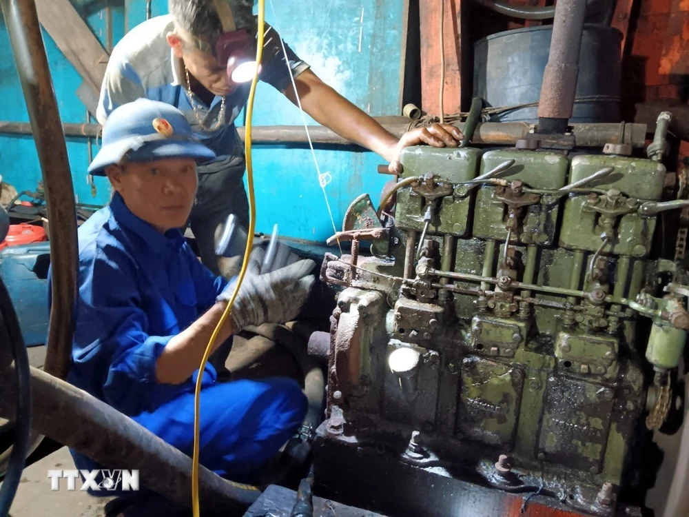 Cán bộ kỹ thuật Âu tàu đảo Sinh Tồn giúp ngư dân sửa chữa máy phát điện của tàu cá QNg 90431 TS. Ảnh: TTXVN phát