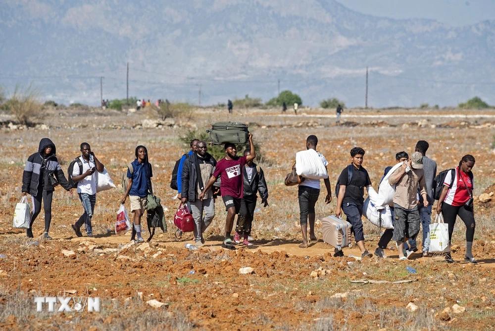 Người di cư rời trại tị nạn Pournara ở CH Cyprus. (Ảnh: AFP/TTXVN)