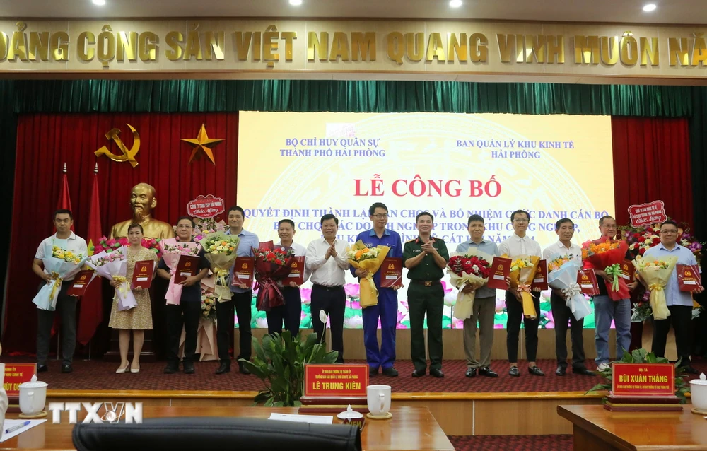 Ông Lê Trung Kiên, Trưởng ban Ban quản lý Khu kinh tế Hải Phòng (thứ 6 từ trái sang) và Đại tá Bùi Xuân Thắng (mặc quân phục) chúc mừng các doanh nghiệp. (Ảnh: Minh Thu/TTXVN)