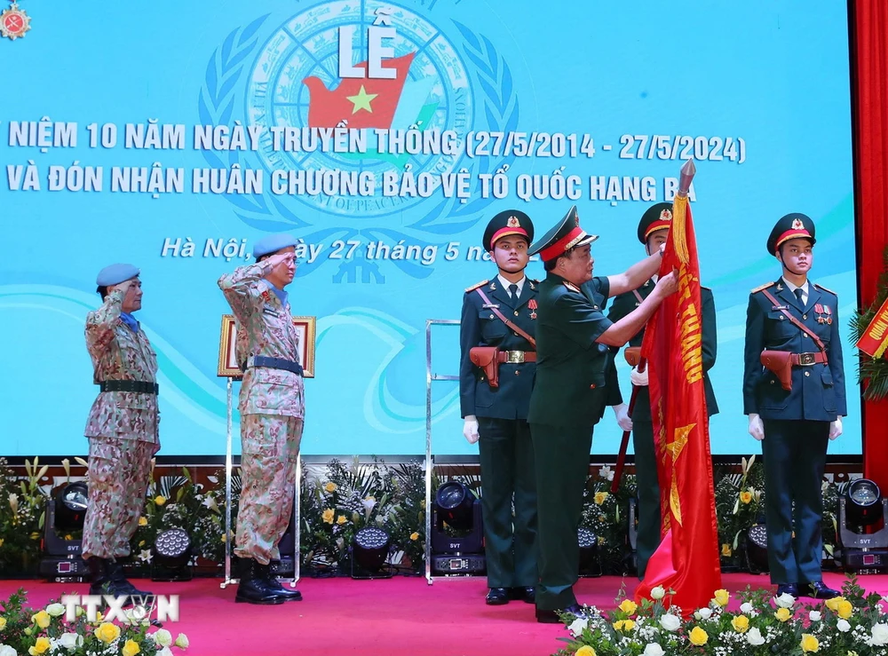 Thượng tướng Hoàng Xuân Chiến, Thứ trưởng Bộ Quốc phòng gắn Huân chương Bảo vệ Tổ quốc hạng Ba lên cờ của Đội Công binh số 1. (Ảnh: Trọng Đức/TTXVN)