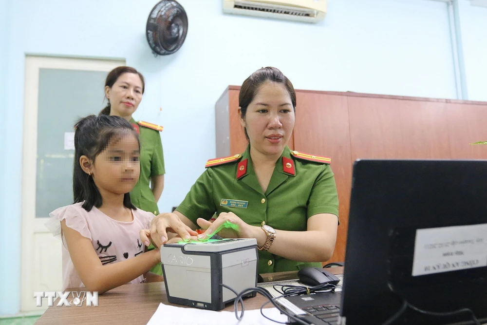 Cán bộ chiến sỹ Đội cảnh sát quản lý hành chánh về trật tự xã hội Công an Quận 10 Thành phố Hồ Chí Minh thực hiện cấp thẻ căn cước, tài khoản định danh điện tử cho trẻ em tại địa phương. (Ảnh: Thanh Vũ/TTXVN)