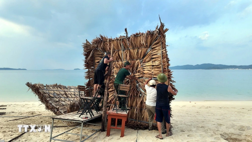 Lực lượng Biên phòng Cô Tô giúp người dân chằng chống cơ sở kinh doanh tại bãi biển Hồng Vàn. (Ảnh: TTXVN phát)