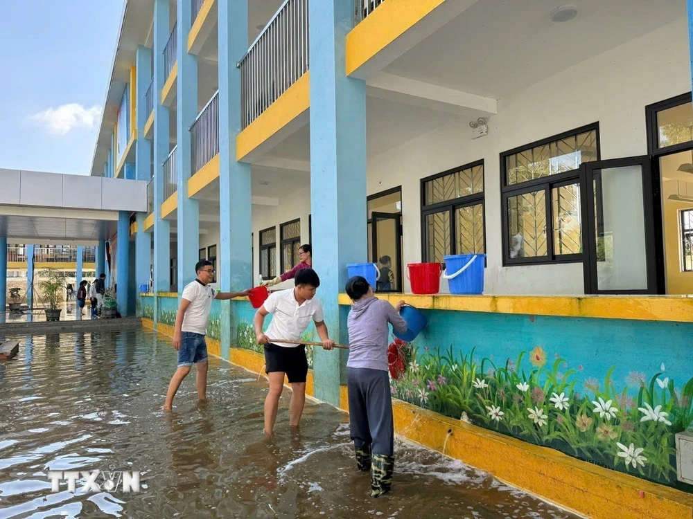 Giáo viên, nhân viên Trường Trung học cơ sở Nam Phương Tiến A dọn vệ sinh trường lớp sau nhiều ngày bị ngập sâu. (Ảnh: Nguyễn Cúc/TTXVN)